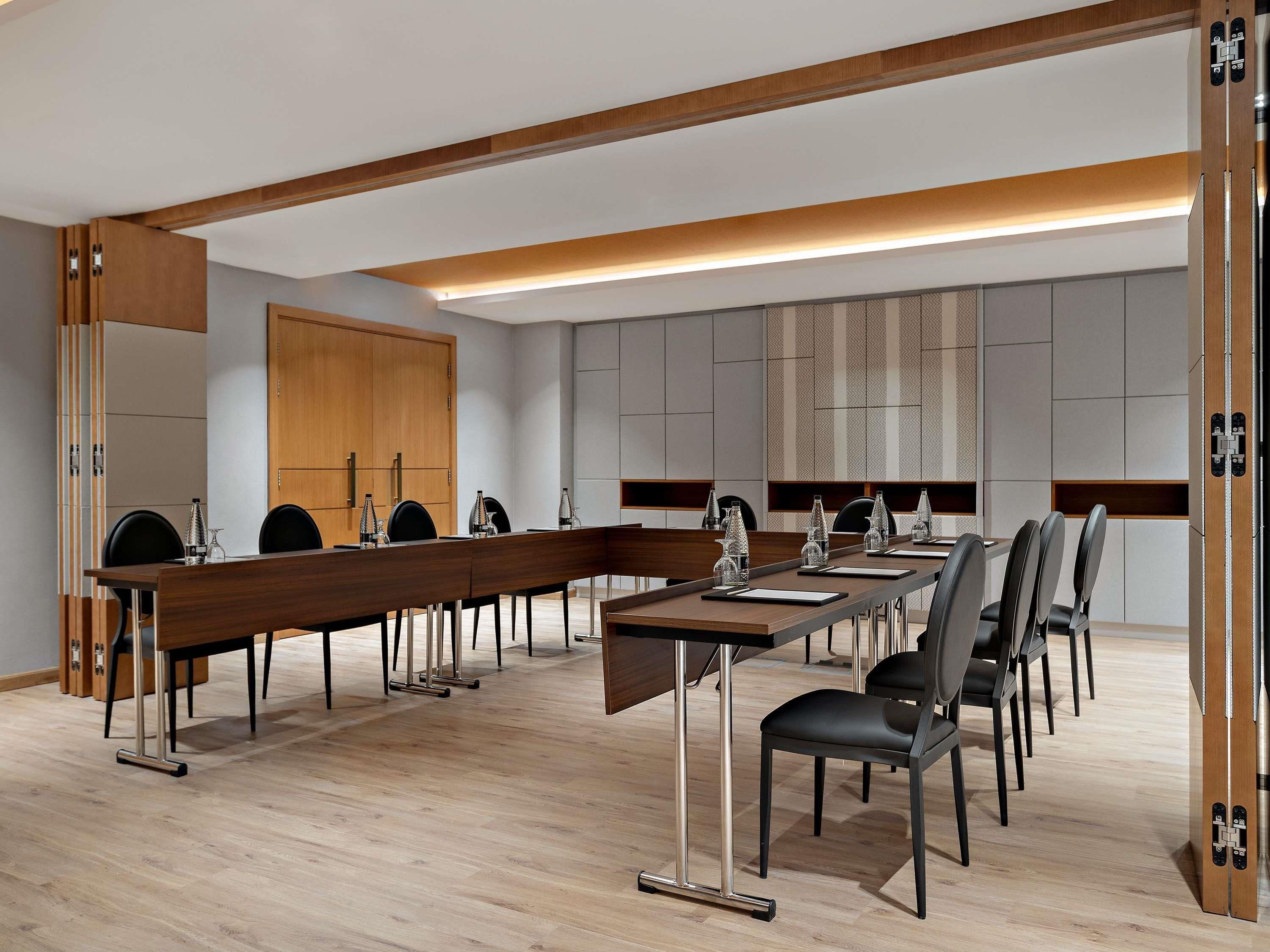 A conference room with a long table, chairs, and a wooden door.