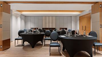 A conference room with round tables, chairs, and a neutral color scheme.