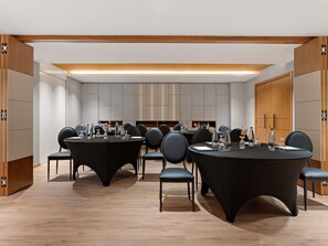 Une salle de conférence dotée de tables rondes, de chaises et d’une décoration aux couleurs neutres.