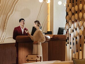 A reception desk with a wooden finish, a check-in counter, and a wall with a decorative string of pearls. - Mercure Abu Dhabi Downtown (Abu Dhabi)