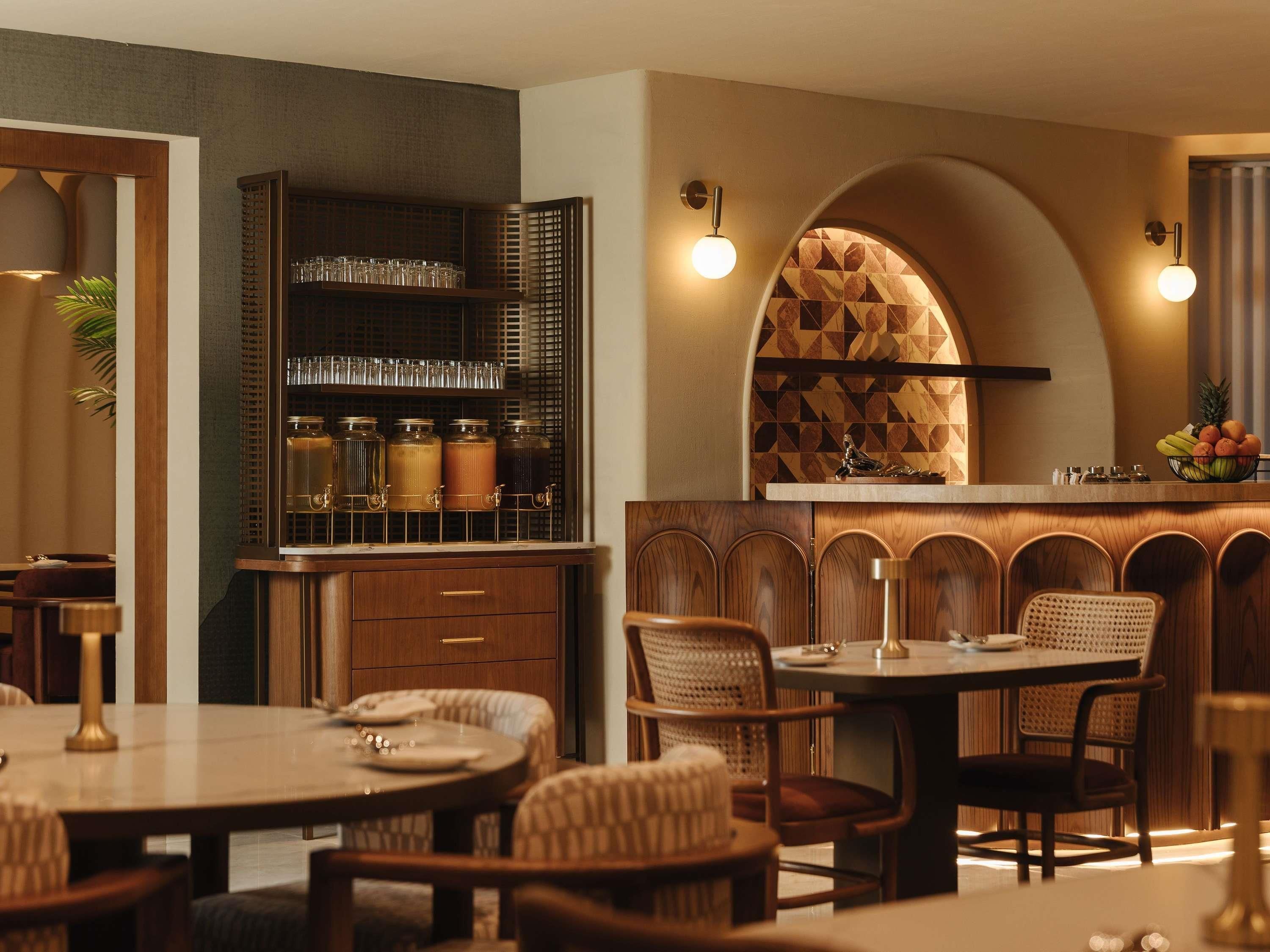 Un restaurant doté d’un bar, de chaises en bois et d’un comptoir sur lequel est posé un panier de fruits.