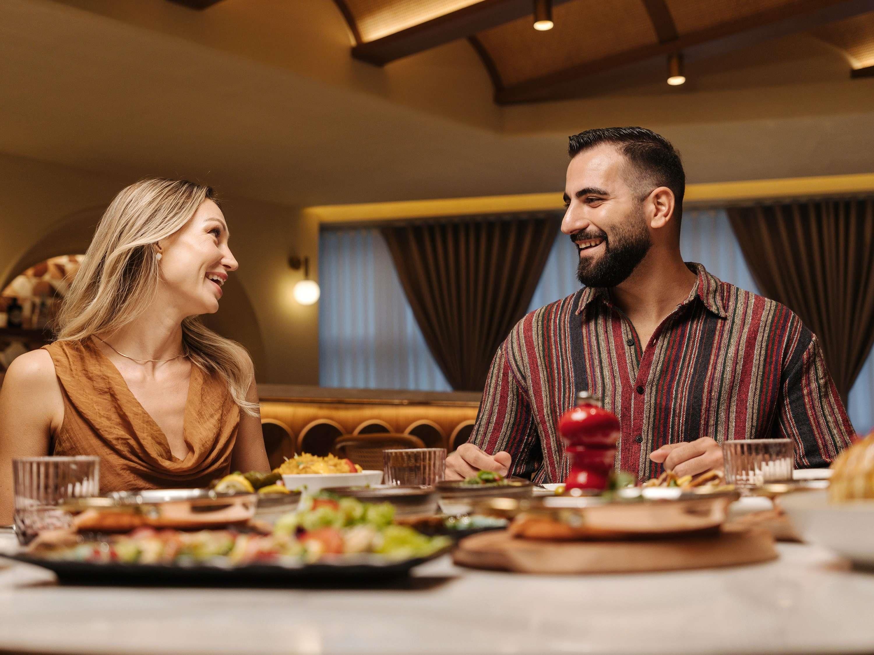 Una pareja cenando en un restaurante con diversos platos sobre la mesa.