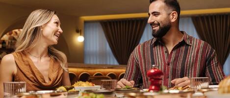 Una pareja cenando en un restaurante con diversos platos sobre la mesa.