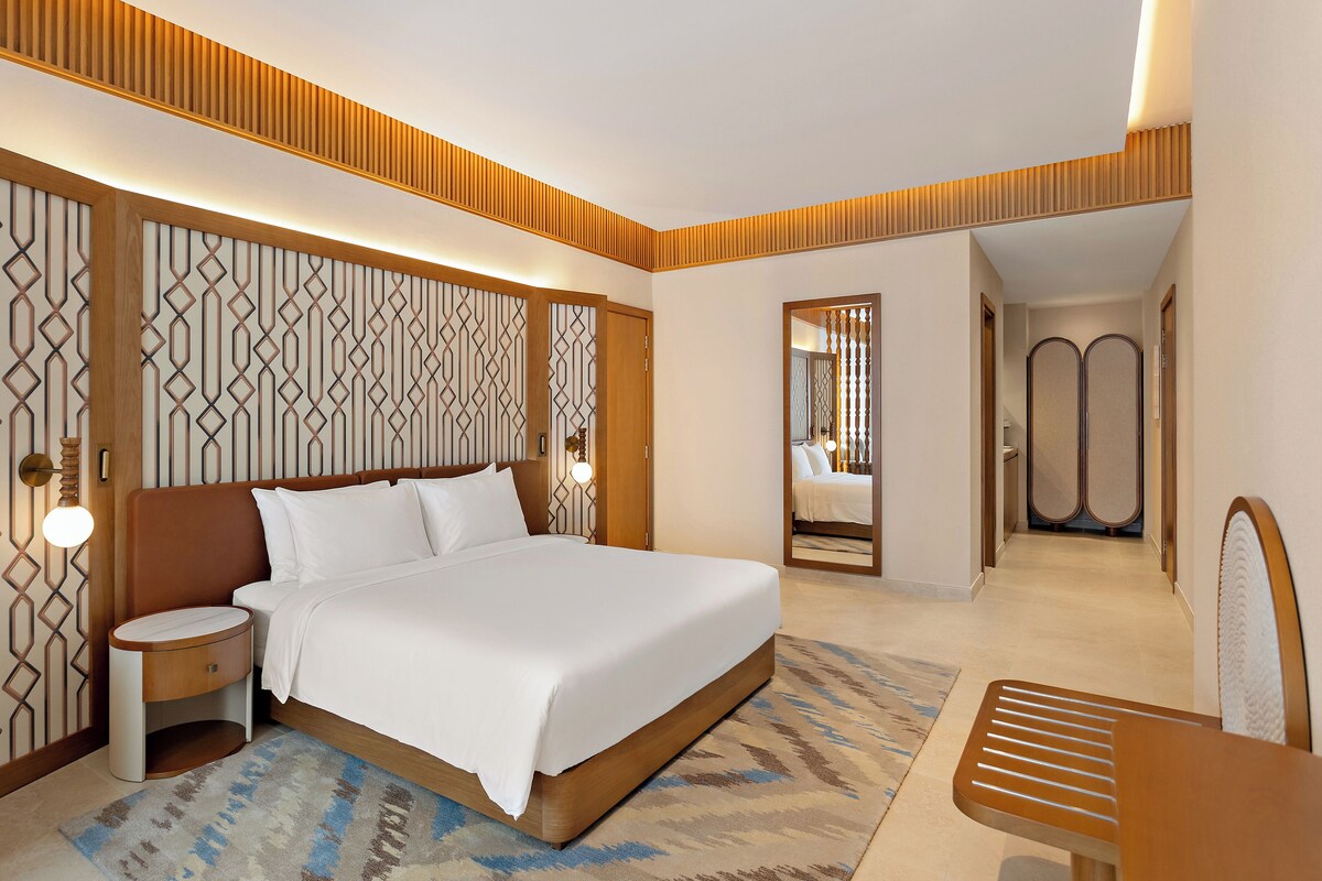 Una habitación de hotel con cama, mesita de noche y espejo.