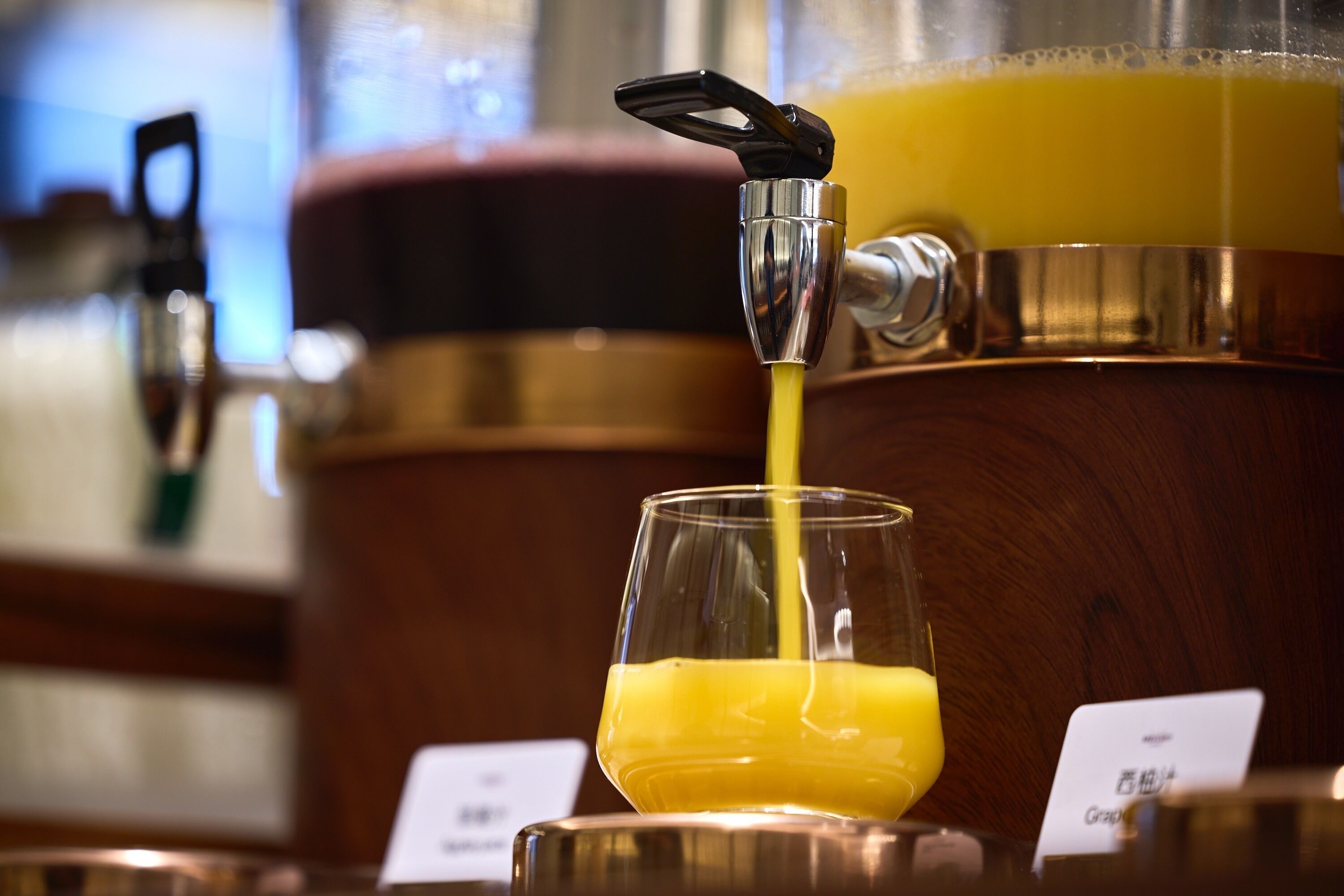 A glass being filled with a yellow liquid from a tap.