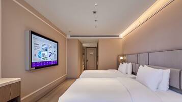 A hotel room with two beds, a flat-screen TV mounted on the wall, and a wooden desk.