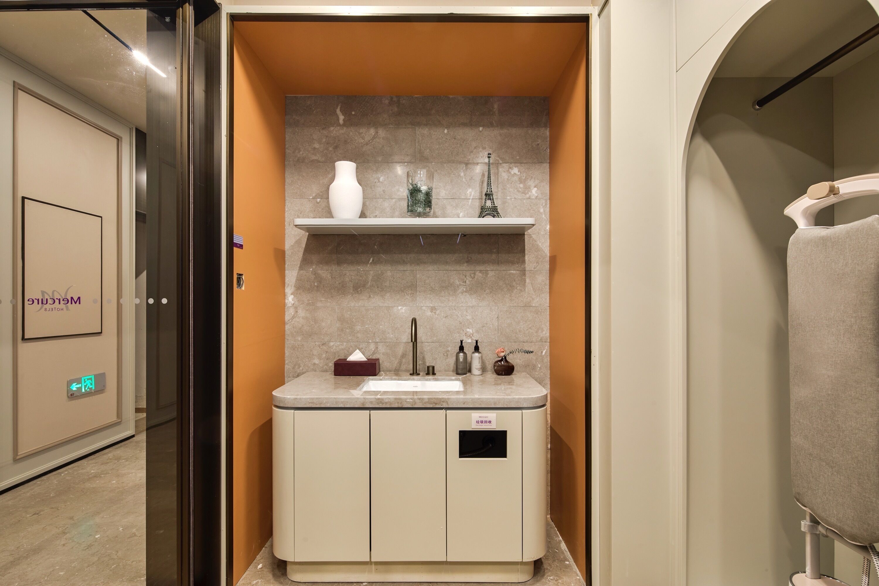 Un baño moderno con encimera de mármol, un lavabo, un espejo y un estante con adornos.