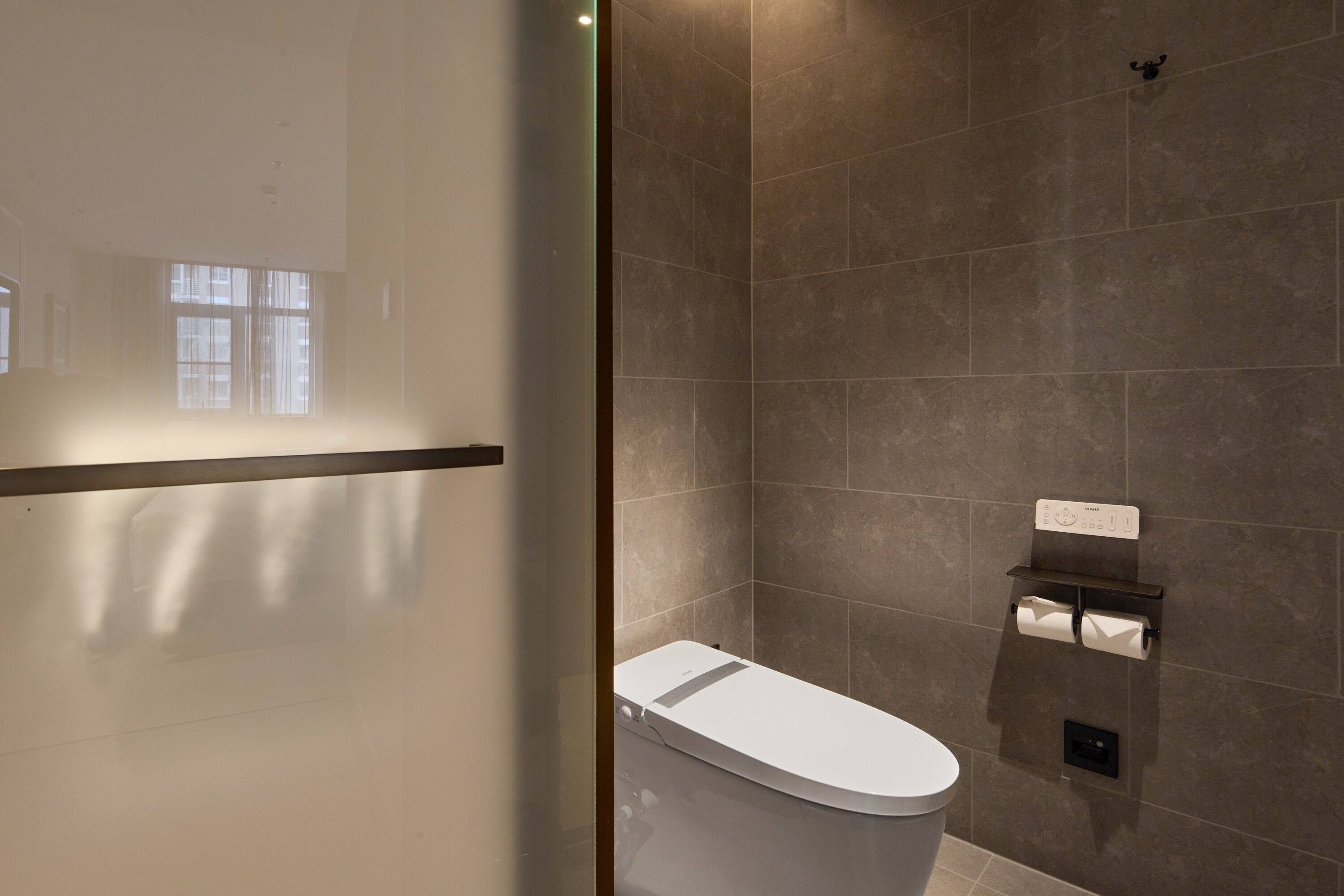 Ein modernes Badezimmer mit Toilette, Handtuchhalter und Toilettenpapierhalter an der Wand.