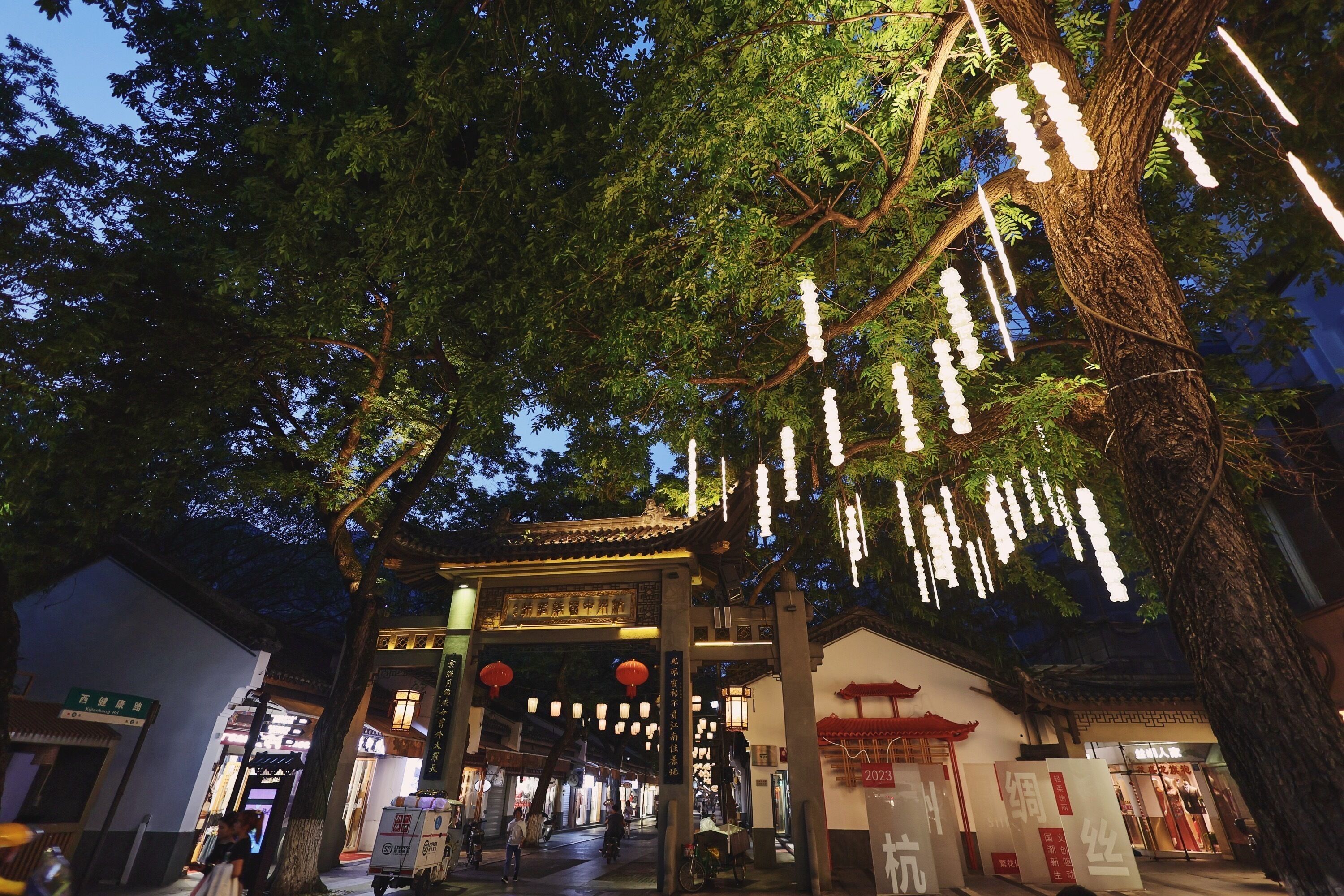 A traditional building with a tiled roof and a large tree in front.