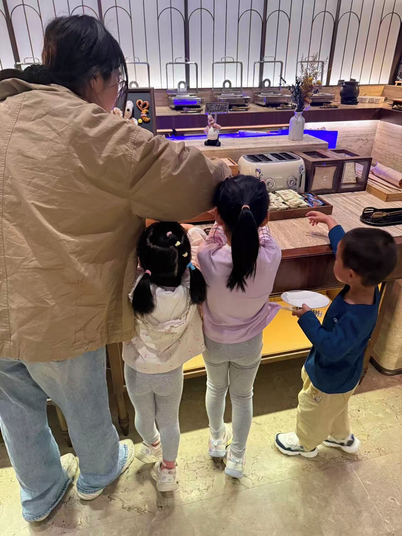 A family interacting with a kitchen setup, including a toaster and a welcome sign.