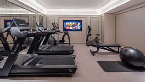 Ein Heimfitnessraum mit Laufbändern, Crosstrainern, einem Ergometer und einem Medizinball.