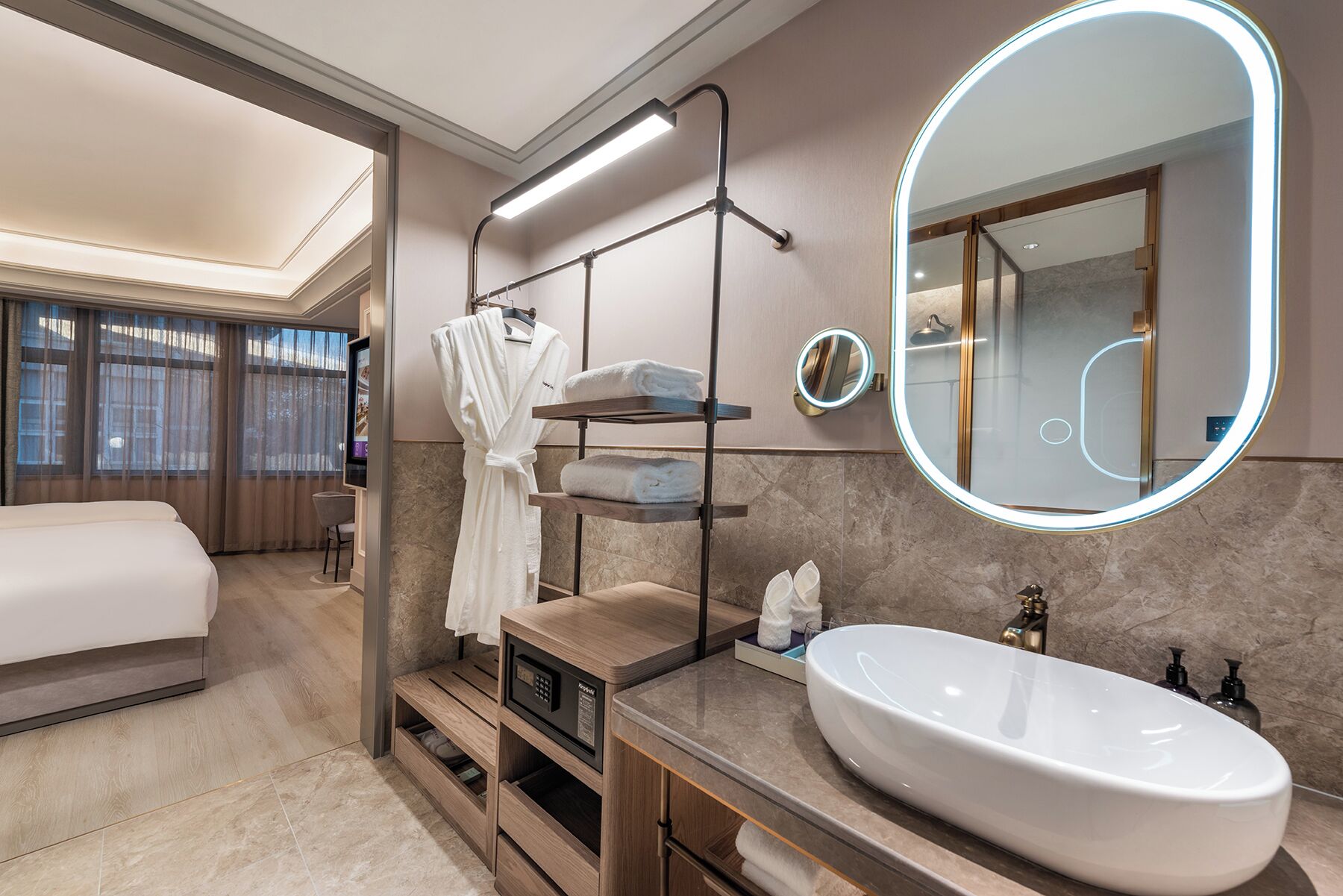 A modern bathroom with a large mirror, a white sink, and a robe rack.