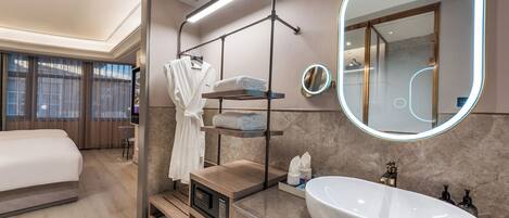 A modern bathroom with a large mirror, a white sink, and a robe rack.
