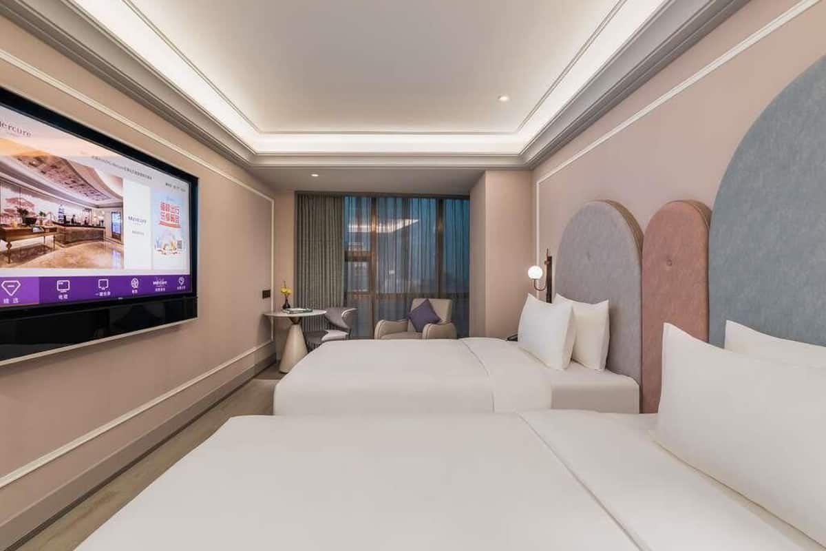 A hotel room with two beds, a flat-screen TV, a small table, and a chair.