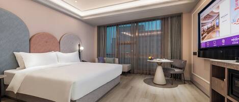 A modern hotel room with a large bed, a desk, and a television.