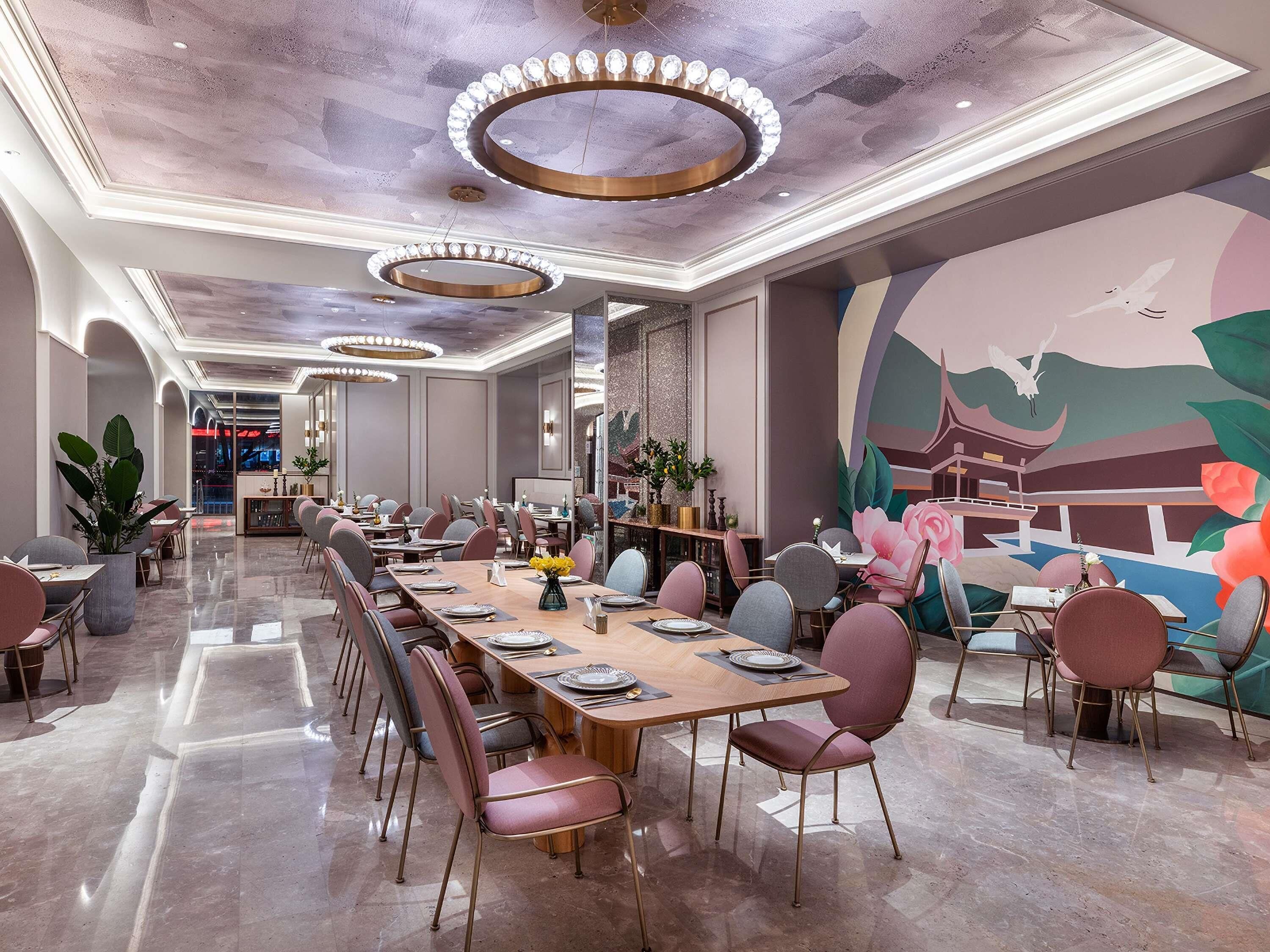 A modern dining area with a long table, chairs, and a mural on the wall.
