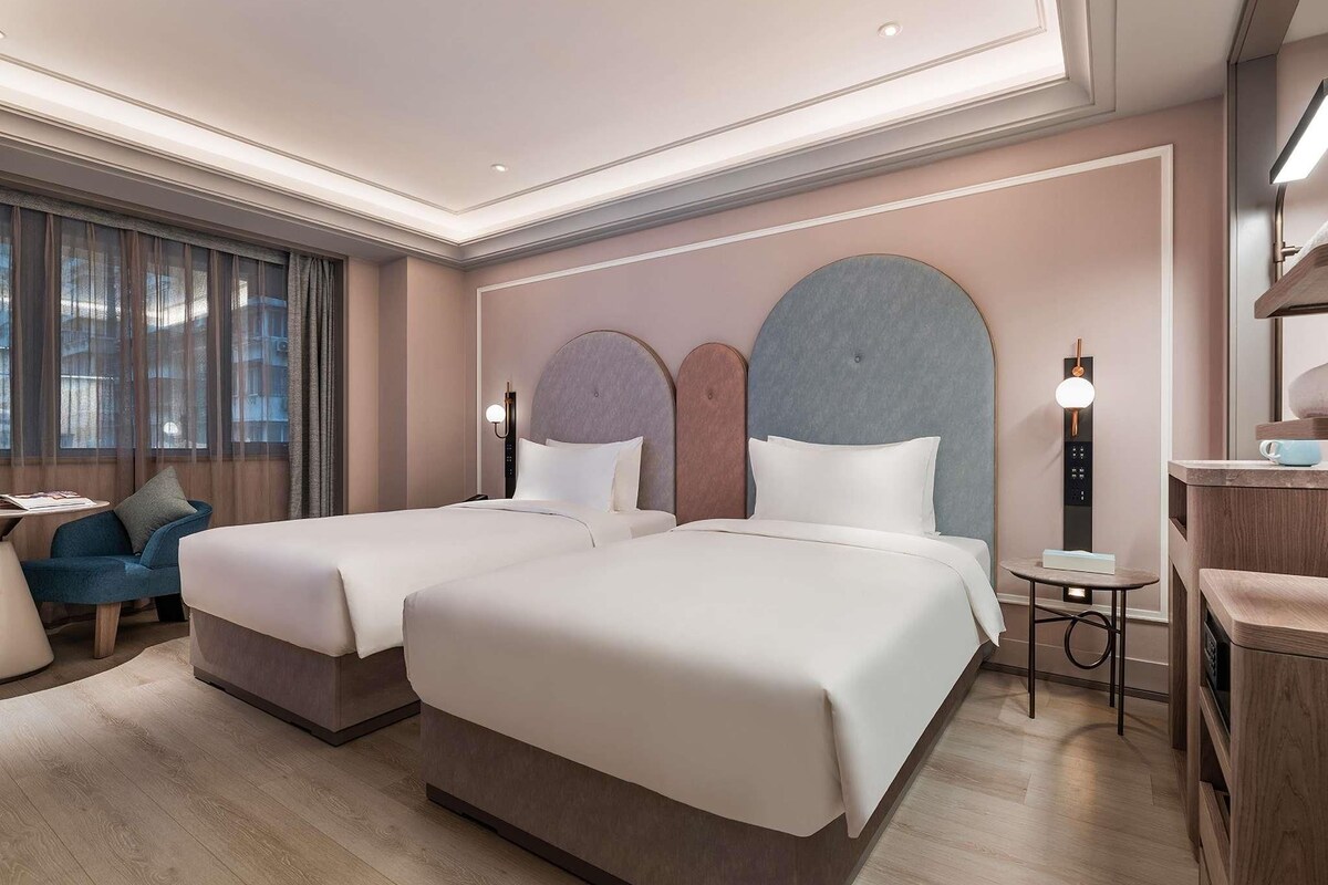 Una habitación de hotel con dos camas, un escritorio, una silla y una mesita.
