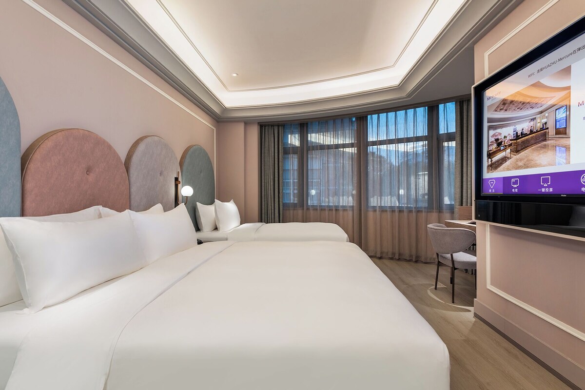 Una habitación de hotel moderna con una cama grande, televisión y escritorio.