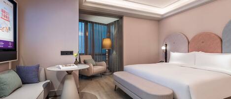 Une chambre d’hôtel moderne avec un grand lit, un canapé, une petite table et un téléviseur.