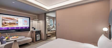 Ein modernes Hotelzimmer mit einem großen Bett, einem Schreibtisch mit Computer, einem Fernseher und einem durchgegangenen Tür angedeuteten Badezimmer.