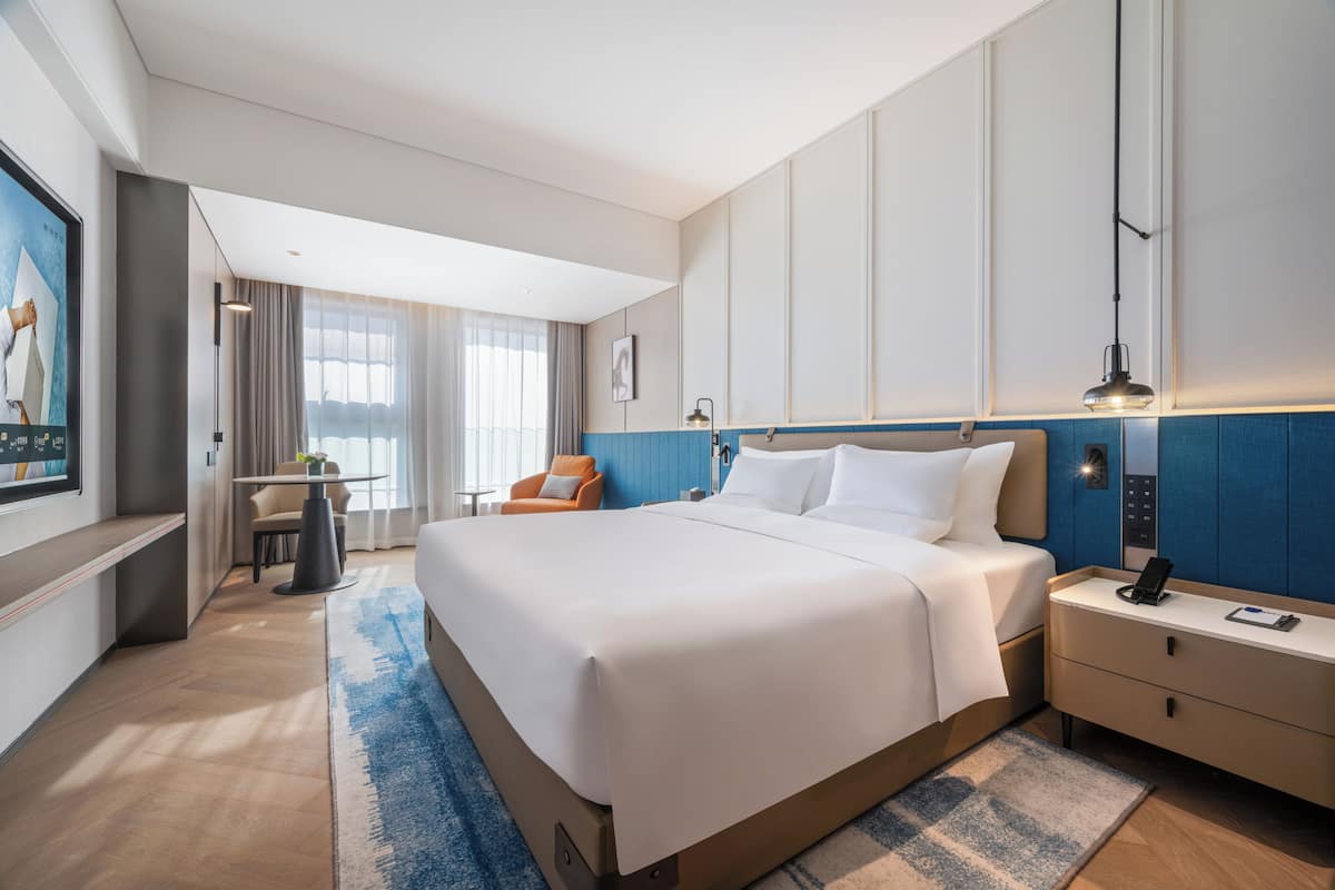 Een hotelkamer met een groot bed, nachtkastjes, een bureau en een stoel.