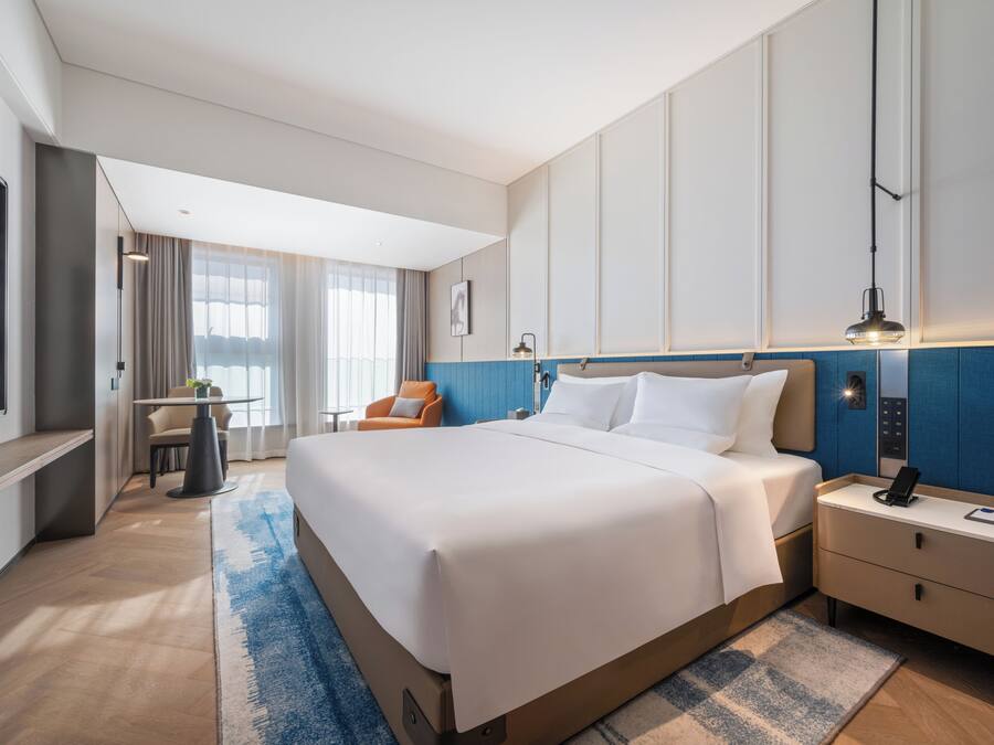 Ein Hotelzimmer mit einem großen Bett, Nachttischen, einem Schreibtisch und einem Sessel.