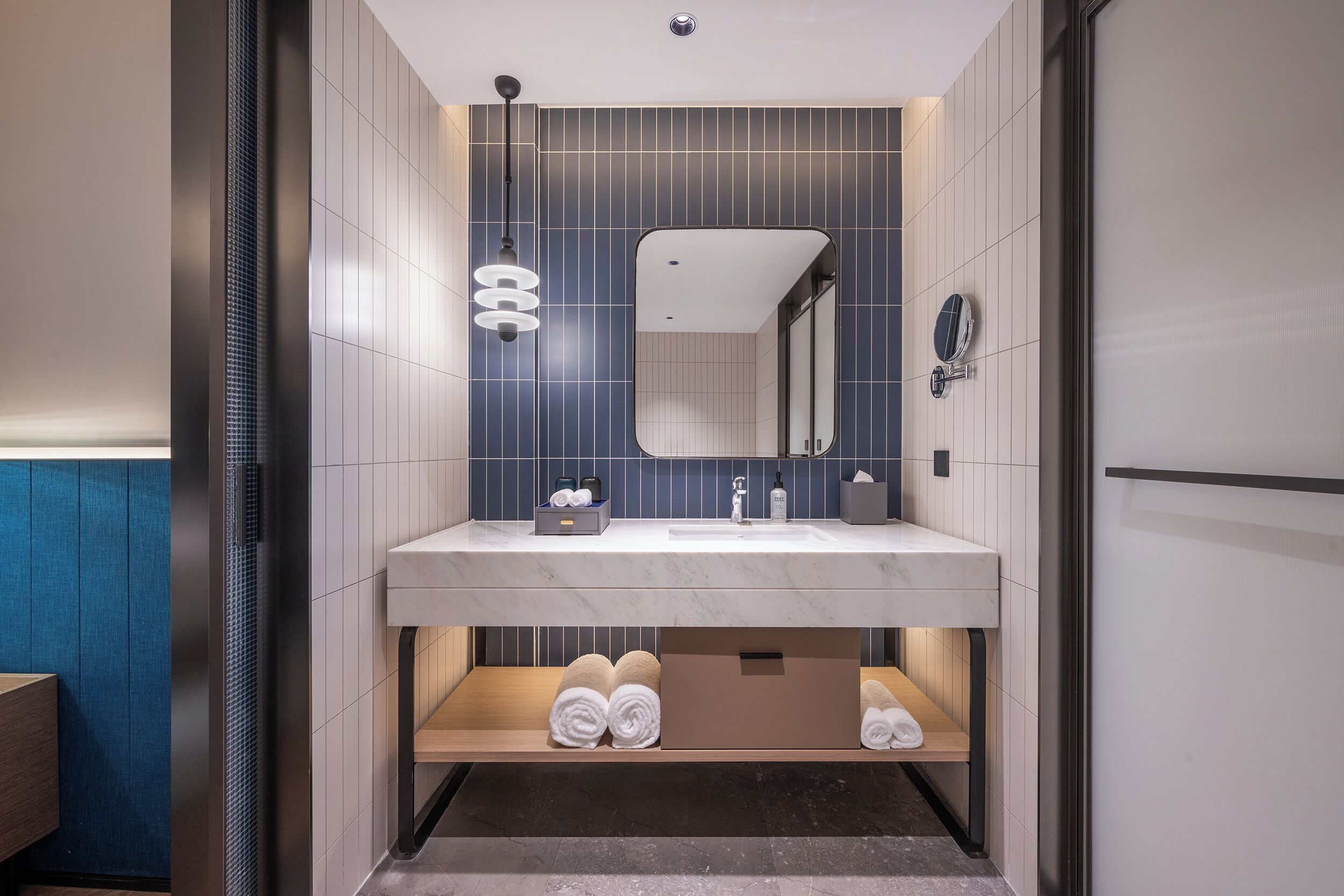 Un baño moderno con lavamanos de mármol, un espejo y un perchero para toallas.
