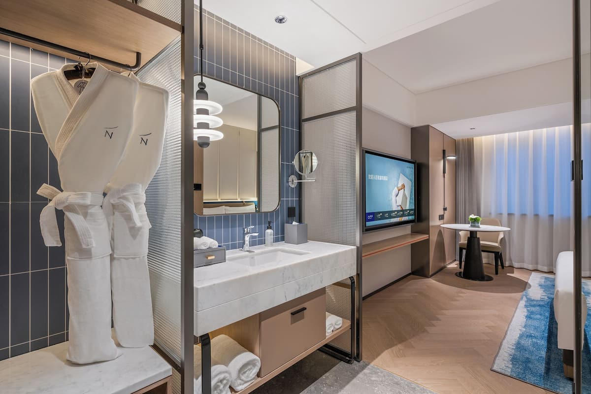 Een moderne hotelbadkamer met een grote spiegel, een wastafel en een televisie.