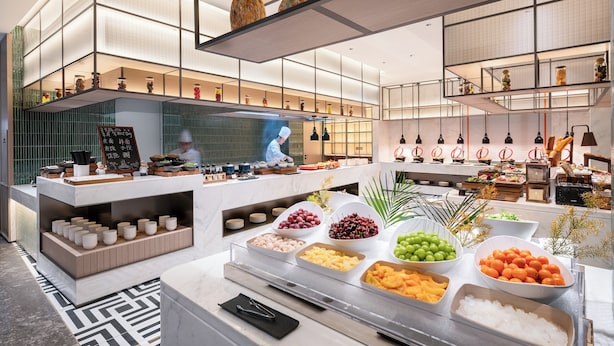 A modern buffet setup with various food items and a chef preparing food. - Novotel Hangzhou Yuhang (Hangzhou)