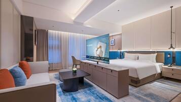 Une chambre d’hôtel moderne équipée d’un lit, d’un canapé, d’une télévision, d’un bureau et d’une table de chevet.