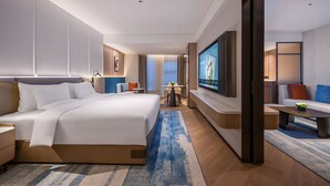 A modern hotel room with a large bed, a TV, a seating area, and a small table. - Novotel Hangzhou Yuhang (Hangzhou)