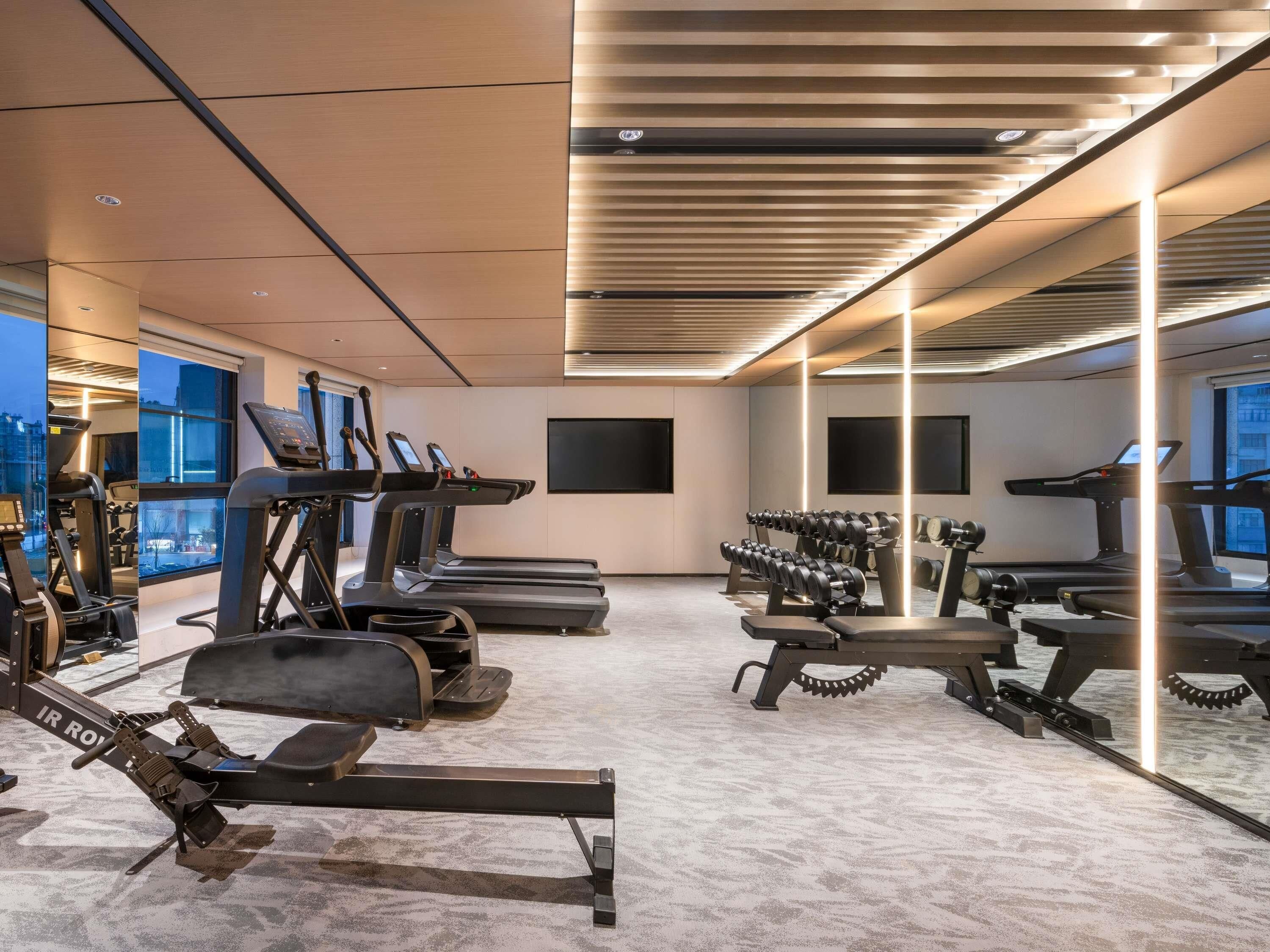 Un gimnasio con cintas de correr, máquinas de remo y mancuernas.