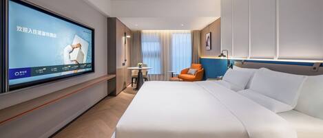 A modern hotel room with a large bed, a television mounted on the wall, a small table, and an orange chair.