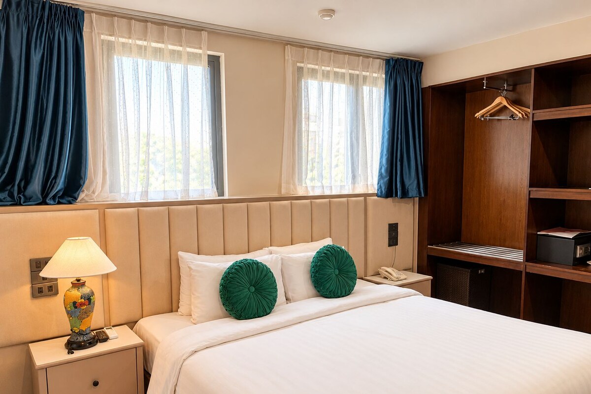 A hotel room with a bed, bedside table, lamp, and a wardrobe.