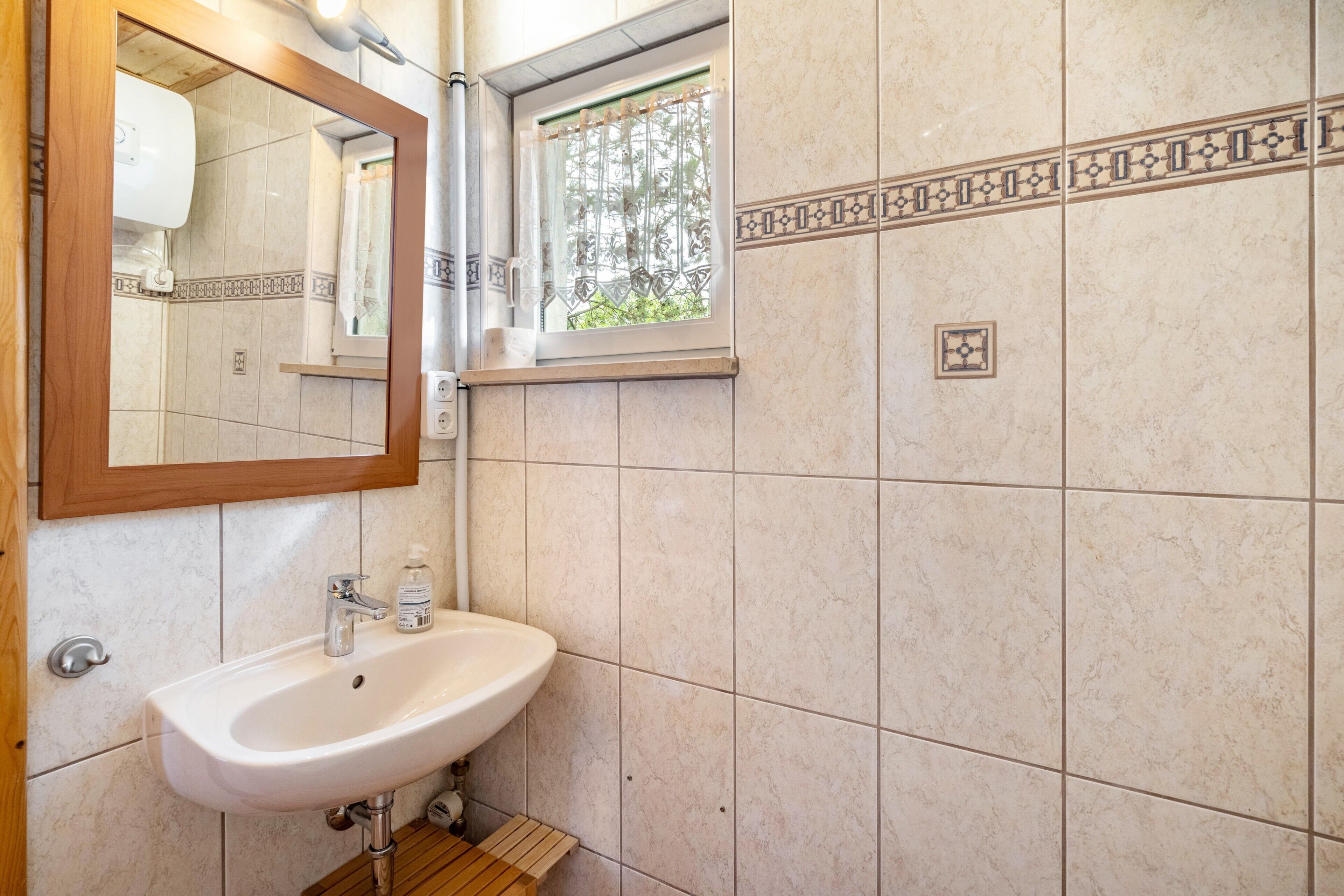 A bathroom with a sink, mirror, and window with a view.