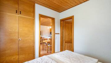 Ein Schlafzimmer mit Holzboden, einem Bett mit weißer Matratze und Holzschränken.