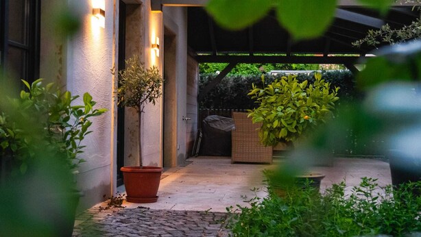 A covered outdoor area with potted plants and a pergola structure.