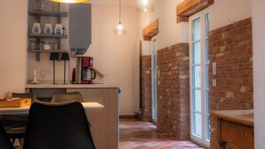 A kitchen with a brick wall, a wooden table, and hanging pendant lights.