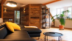 A modern living room with a sectional sofa, a small round table, and a potted plant.