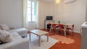 Ein modernes Wohnzimmer mit einer Couch, einem Couchtisch, einem Fernseher und einem Essbereich mit Stühlen und einem Tisch.