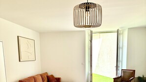 A modern living room with a dining area, featuring a large wooden table, red chairs, a brown sofa, and a hanging light fixture. - Apartment Azzura, Villa Cana private garden (Cannes)