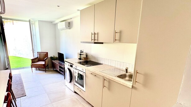 A modern kitchen with a dining area, large windows, and a view of the outdoors. - Apartment Azzura, Villa Cana private garden (Cannes)