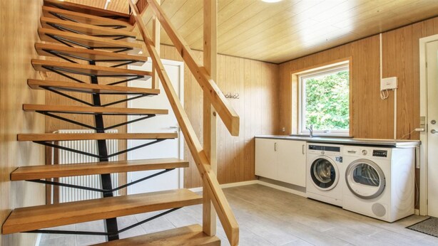 Eine Holztreppe führt zu einem Waschraum mit Waschmaschine und Trockner.