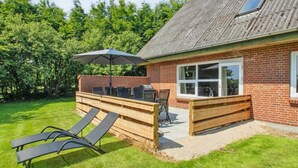 Ein Garten mit Grillplatz, einer Holzterrasse und einem Rasen.