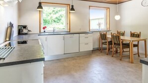 Eine moderne Küche mit weißen Schränken, einer zentralen Kochinsel und einem Essbereich mit Holztischen und einer Tischplatte.