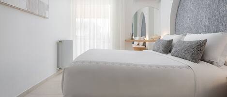 A modern hotel room with a large bed, a bedside table, a mirror, and a view of the city.