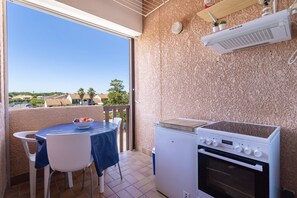 Un balcon équipé d’une table, de chaises, d’un petit réfrigérateur et d’une cuisinière.