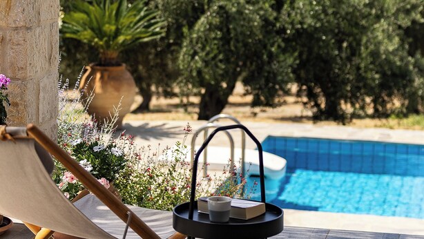 Ein Poolbereich mit Liege, einem kleinen Tisch mit Tablett und Blick aufs Meer.