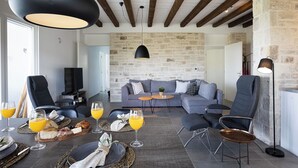Ein modernes Wohnzimmer mit Steinwand, einem grauen Sofa und einem Essbereich mit Frühstücksaufstellung.