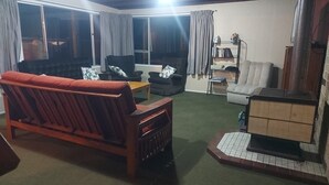 A living room with a sofa, armchairs, a coffee table, and a fireplace. - Waiwhare On The Beach (beachfront property with direct beach access) (Castlepoint)